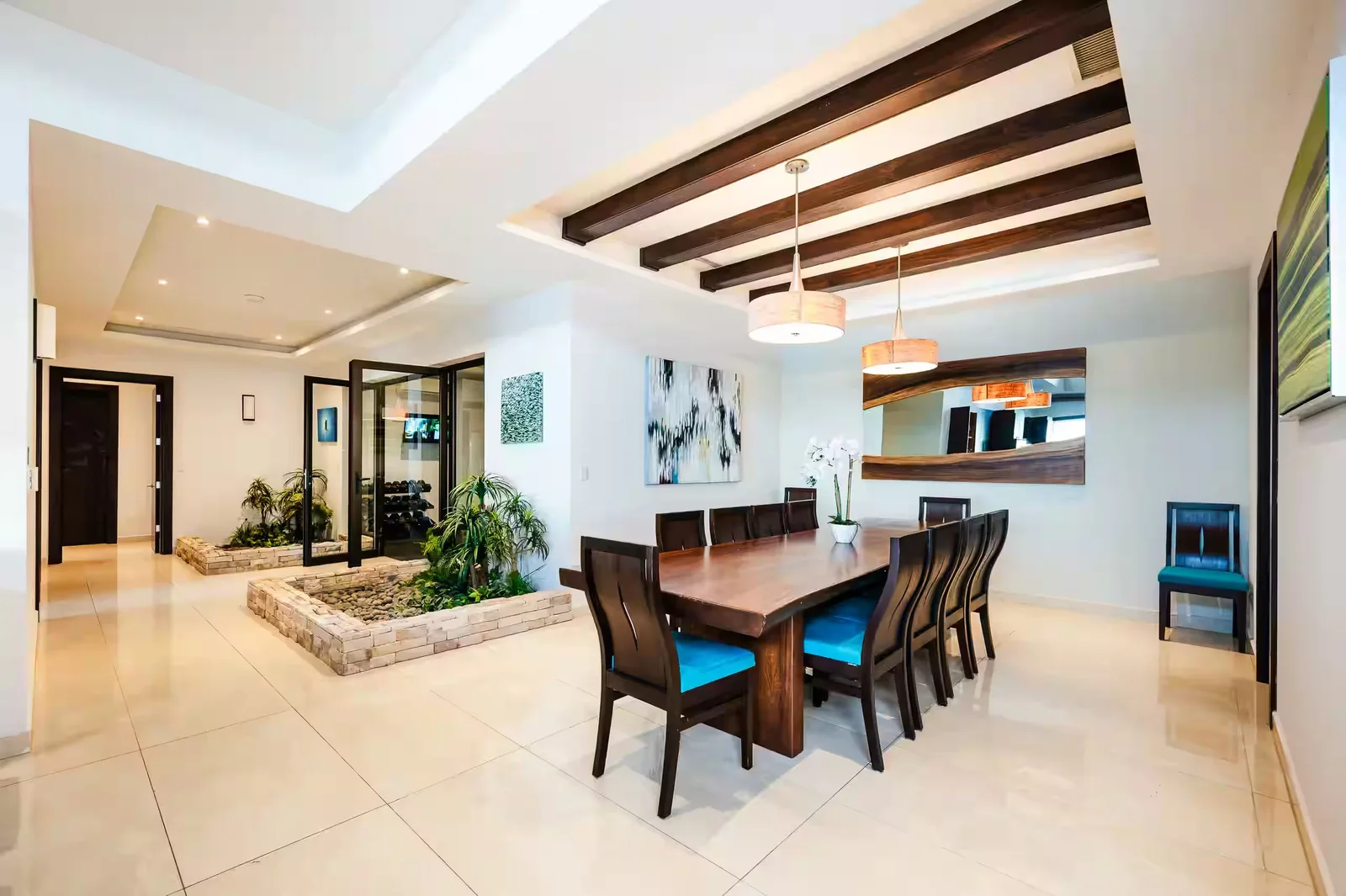 Long dining table seating ten, with the villa's gym behind glass doors