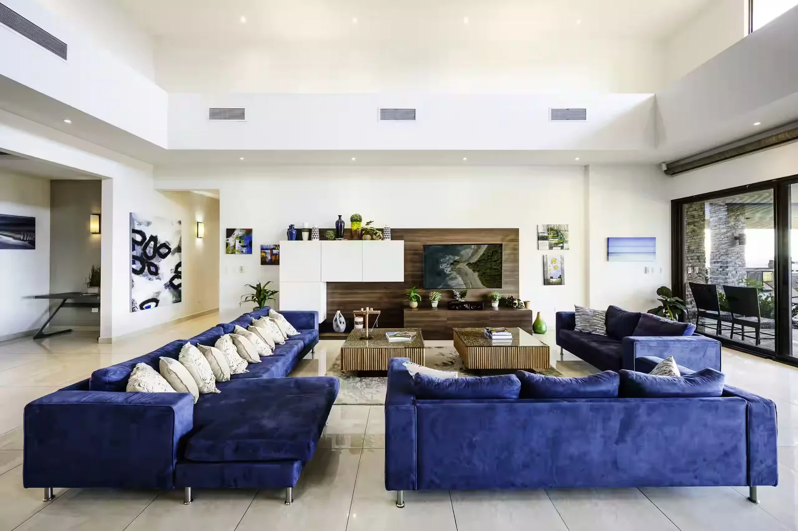 The villa's open living room with deep blue sofas and double-height ceilings