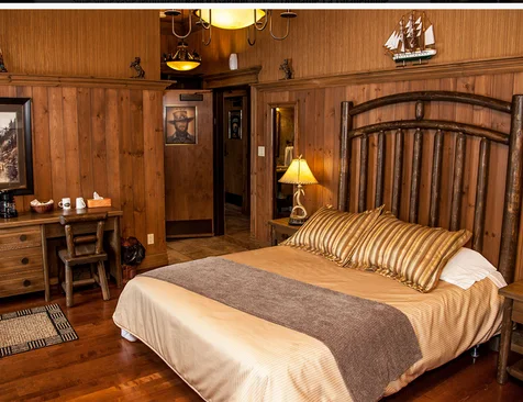 Private room with a double bed, wood-panelled walls and a writing desk