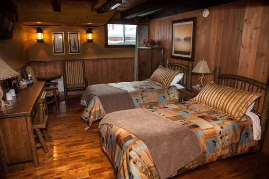 Shared room with two single beds, wood-panelled walls and a writing desk