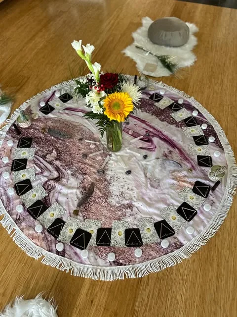 A ceremony circle laid out with flowers, cards and a singing bowl