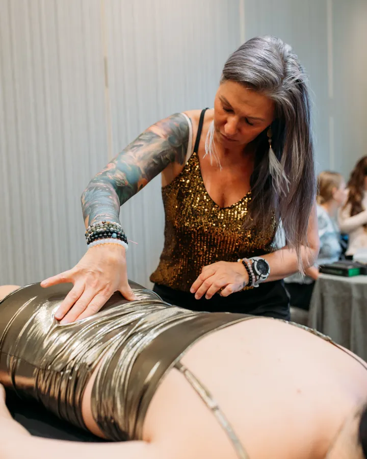 Jen resting one flat hand on a client's back as she lies face down on the table